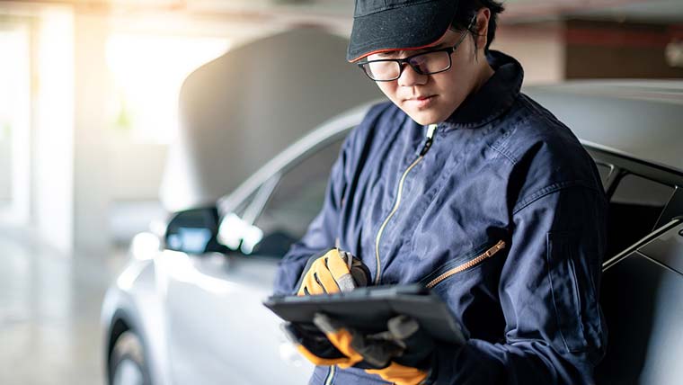 An auto body shop technician holding a tablet